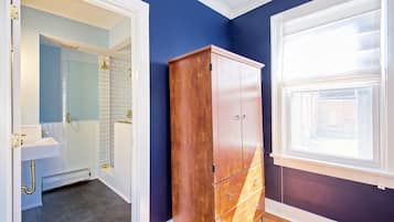 A bathroom with a wooden cabinet, a window, and a tiled shower area.