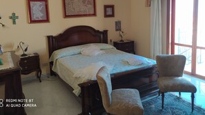 Een slaapkamer met een bed, nachtkastjes, een stoel en een kroonluchter.