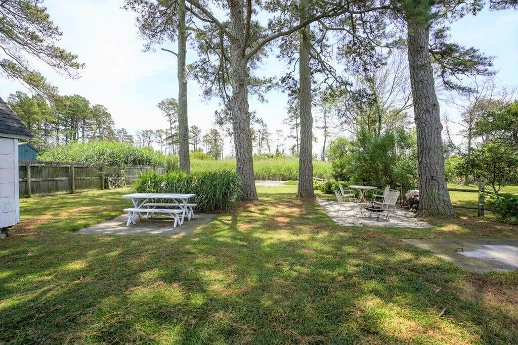A backyard with a picnic table and chairs, surrounded by trees and a wooden fence.