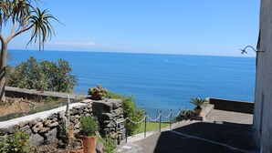 Une vue sur la côte, avec un mur de pierre, des plantes en pot et un ciel bleu dégagé.