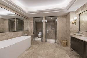 Um banheiro moderno com uma banheira grande, chuveiro com box de vidro e toucador com espelho e luminária.