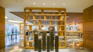 Un interior moderno con una exhibición central de objetos decorativos, un panel de madera y un piso de m ármol pulido.