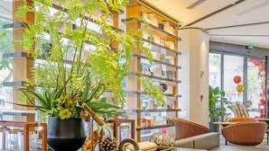 Un interior moderno con una mesa central de madera y negro, rodeada de asientos y una planta grande en maceta.