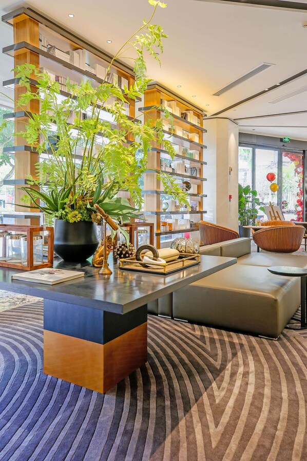 A modern interior with a central black and wooden table, surrounded by seating and a large potted plant. - Best Western Plus Haiyue Hotel Fuzhou (Fuzhou)