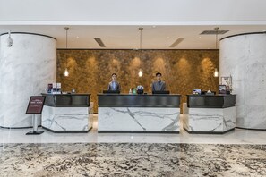 A hotel reception area with marble reception desks, a hexagonal patterned wall, and pendant lighting. - Best Western Plus Haiyue Hotel Fuzhou (Fuzhou)