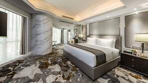 Una habitación de hotel moderna con una cama grande, columna de mármol y vistas a la ciudad.