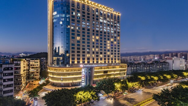 Un hotel moderno de gran altura, con varios pisos, una entrada destacada y una fachada bien iluminada.