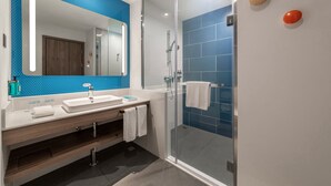 Un baño moderno con cabina de ducha de vidrio, un espejo grande y pared con azulejos azules.