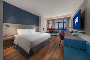 A modern hotel room with a large bed, a seating area, a TV, and a city view. - Holiday Inn Express Yangquan City Center by IHG (Yangquan)