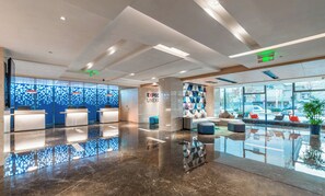 A modern reception area with a glass partition, reception desks, and a seating area with a view of the street. - Holiday Inn Express Yangquan City Center by IHG (Yangquan)