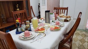 Een eettafel gedekt met verschillende gerechten en kruiden, omringd door houten stoelen.