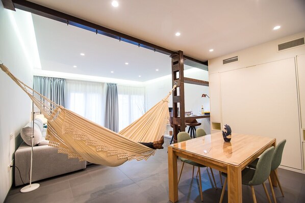 Relax in a serene space with a dining table, comfortable sofa, and hammock.