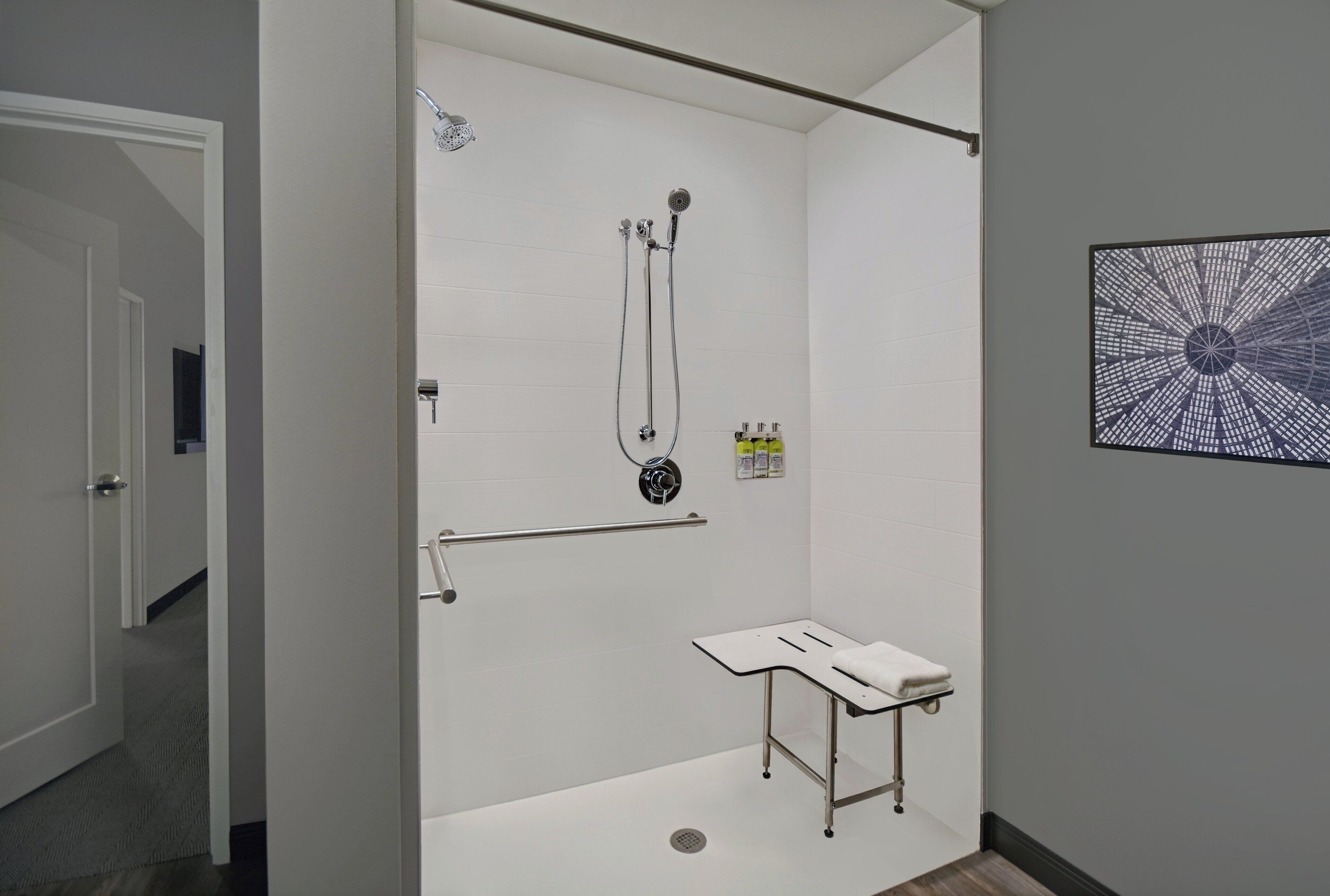 A modern bathroom with a walk-in shower, a toilet with a raised seat, and a towel rack.