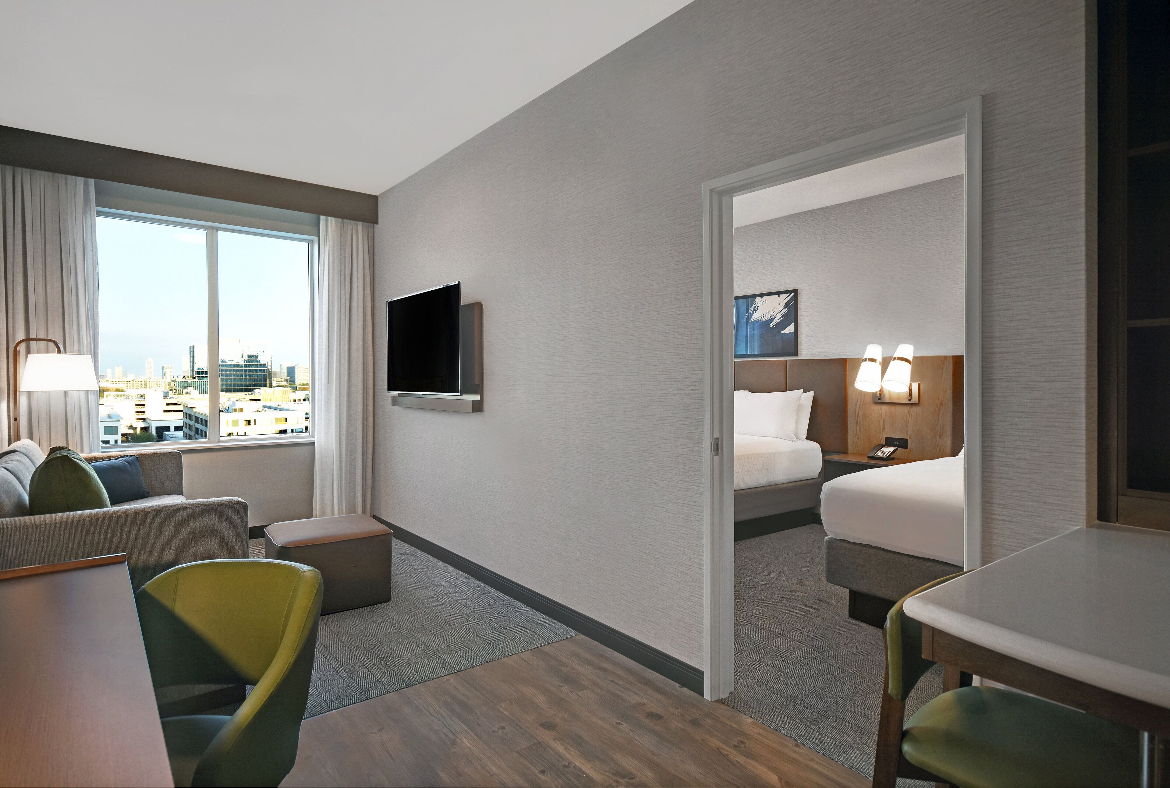 Une chambre d’hôtel dotée d’une grande fenêtre, d’un téléviseur à écran plat, d’un lit, d’un bureau et d’une chaise.