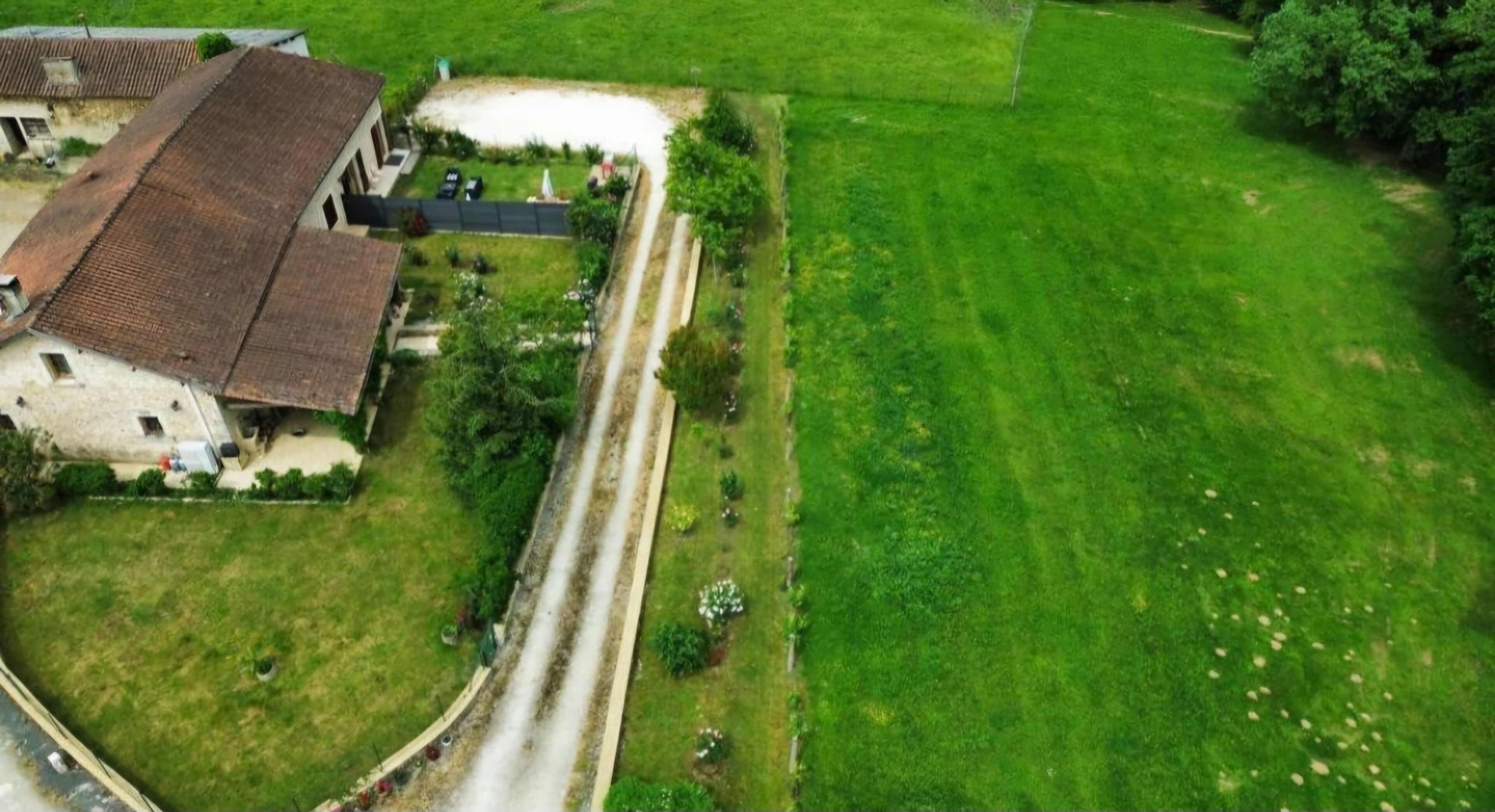 Vue aérienne d’une propriété comprenant un grand bâtiment, une allée et une pelouse bien entretenue.