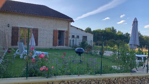 Une maison en pierre avec un jardin, un espace extérieur aménagé et un barbecue.