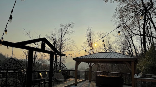 A covered outdoor deck with string lights, a gazebo, and a swing set.