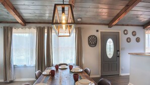 A dining room with a wooden table set for six, a chandelier, and a door with decorative glass panels.