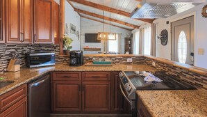 A kitchen with wooden cabinets, granite countertops, a built-in oven, and a stainless steel range hood.