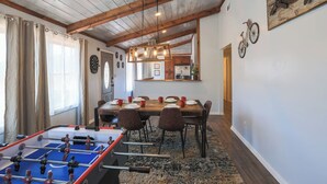 A dining area with a wooden table, chairs, and a foosball table.