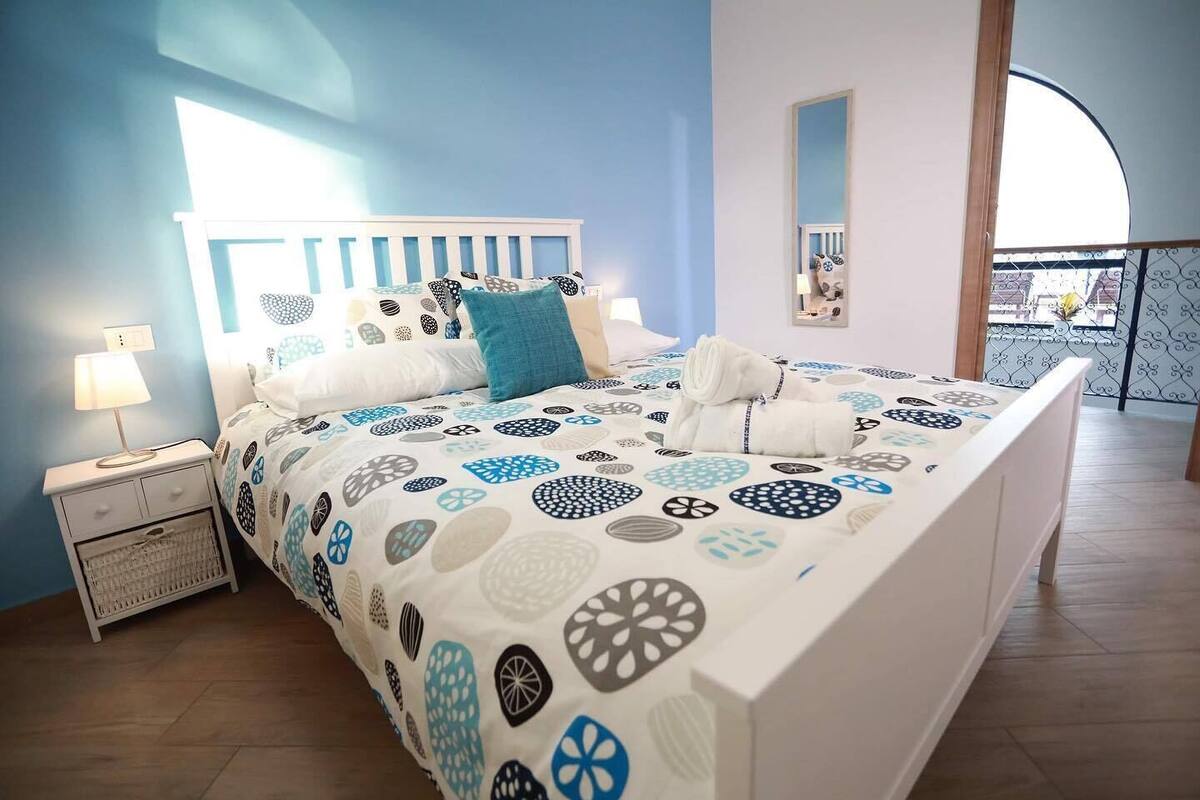 Un dormitorio con cama, mesita de noche y espejo.