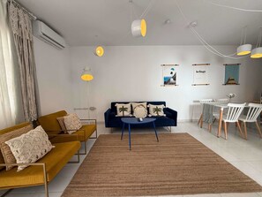 A modern living room with a sofa, coffee table, and a dining area with chairs and a table.