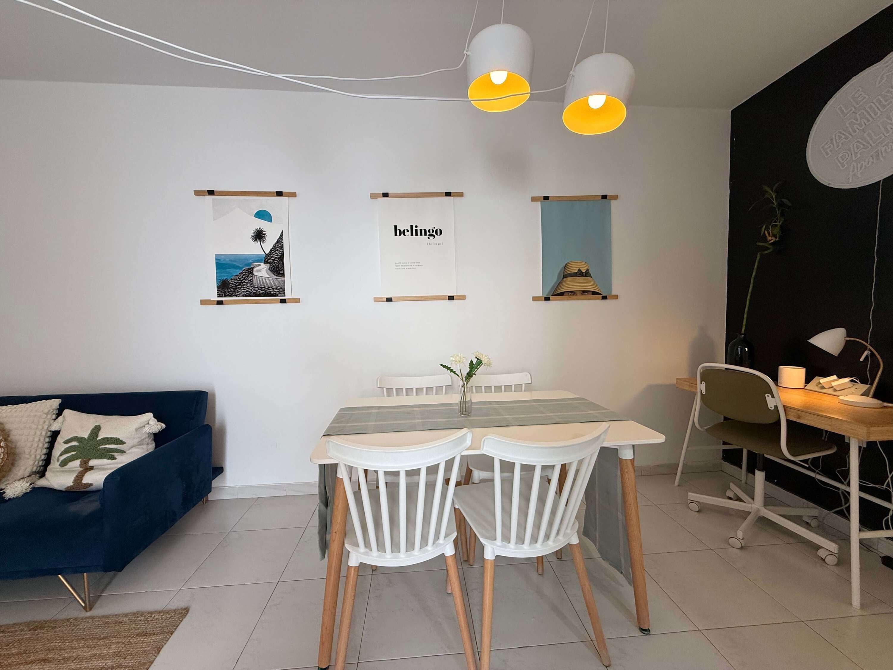 A modern dining area with a table, chairs, and hanging pendant lights.