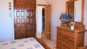 Quarto com cama de madeira, penteadeira, cadeira e espelho.