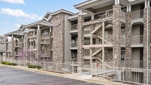 A multi-story hotel with stone pillars, balconies, and a parking lot.