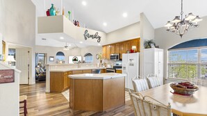 A spacious kitchen with wooden cabinets, a central island, and a dining area with a chandelier.