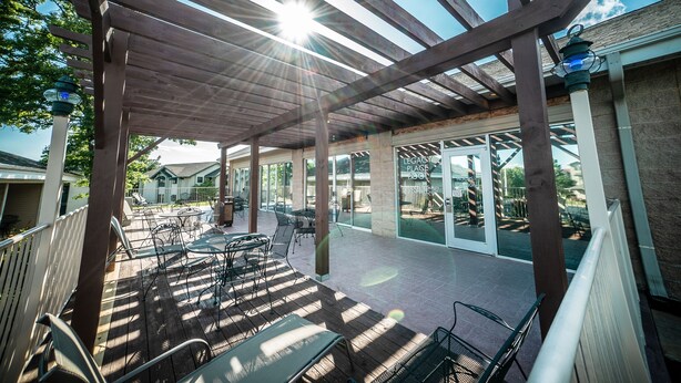 An outdoor patio with wooden pergola, tables, and chairs.