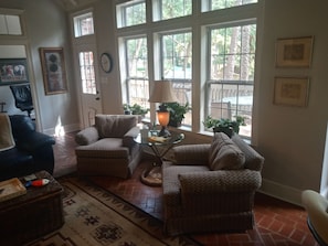 Relax in this inviting living room with a comfortable seating area, brick floor, and framed artwork.