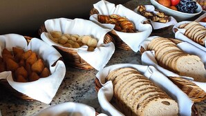 A variety of breads and pastries in baskets on a countertop. - Hotel 7 Itajaí by RB Hotelaria (Itajai)