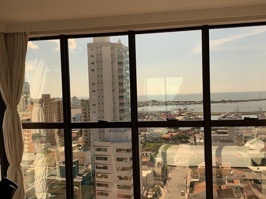 A room with a large window offering a view of a cityscape and a body of water.