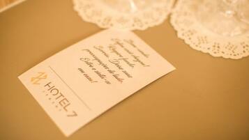 Une chambre d’hôtel avec une table beige, un chemin de table blanc et une carte aux couleurs de l’hôtel.