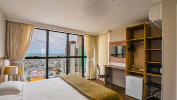 A hotel room with a bed, a desk, a chair, a TV, and a mini-fridge.