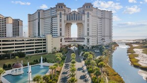 A large hotel with a central archway, a swimming pool, and a river in the background. - 2/2 Townhome North Beach Resort- Pools, Hot tubs, (North Myrtle Beach)
