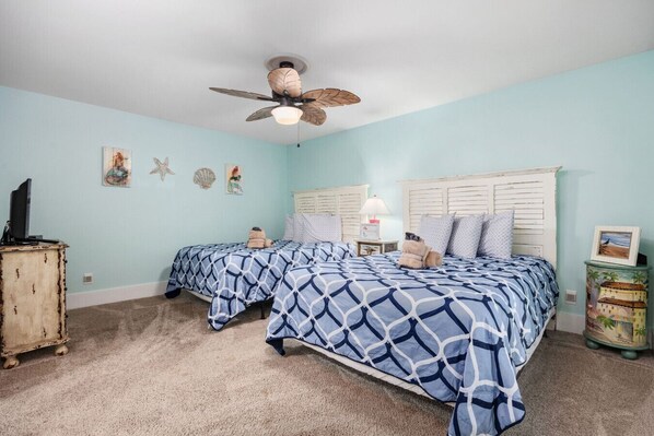 A bedroom with two beds, a ceiling fan, and a dresser.