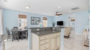A spacious kitchen with a granite island, light blue walls, and a dining area with wooden chairs. - 2/2 Townhome North Beach Resort- Pools, Hot tubs, (North Myrtle Beach)
