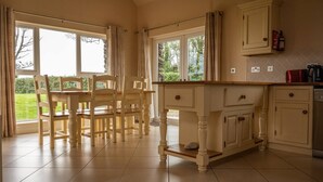 A kitchen with a dining table and chairs, large windows, and a tiled floor. - House 3 Dingle Manor Remarkable 3-Bed House (Dingle)