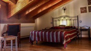 Ein Schlafzimmer mit Holzboden, einem Bett mit gestreifter Decke, einem Stuhl und einem Nachttisch.