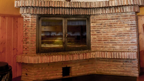 A brick fireplace with a glass door, set in a wooden wall.