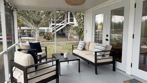 Ein überdachter Patio-Bereich mit Sofagarnitur, einem kleinen Tisch und einer Korb-Hängeleuchte.