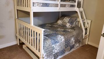 A bunk bed with a ladder, patterned bedding, and a door to the right.