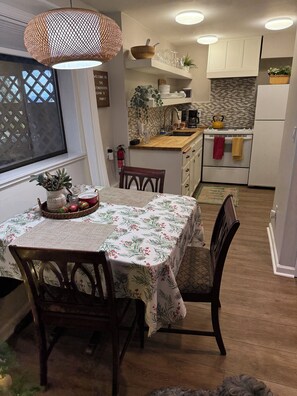 A kitchen with a dining area, wooden cabinets, a tiled backsplash, and a hanging light fixture. - 	
Tranquil Forest Escape-Extended Stays Welcome  (Oregon City)