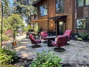 Una casa de madera con un patio que incluye mobiliario exterior y una hamaca.