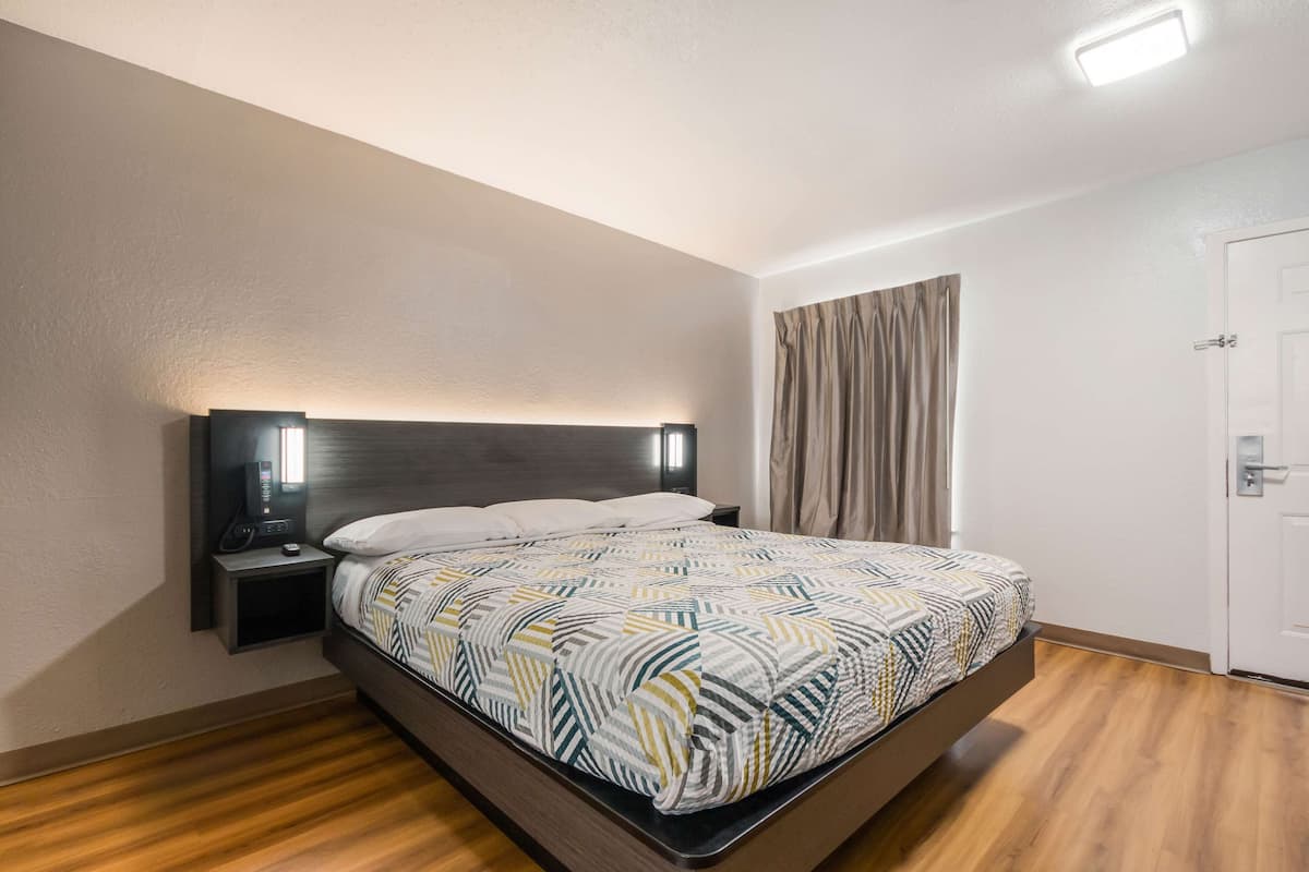 A modern hotel room with a bed, bedside table, and a nightstand.