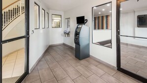 A modern hotel lobby with a self-service kiosk, a staircase, and a large mirror reflecting the interior. - Studio 6 Laredo, TX - North I-35 (Laredo)