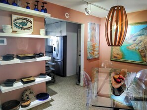 Una cocina moderna con electrodomésticos de acero inoxidable, platos decorativos y un comedor con cristalería transparente.