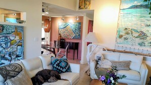 A living room with two white sofas, a wooden coffee table, and a painting of a seascape.